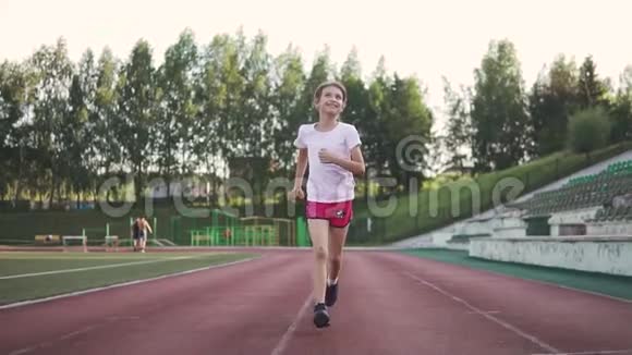 小女孩在体育场慢跑这孩子在露天参加运动孩子们运动视频的预览图