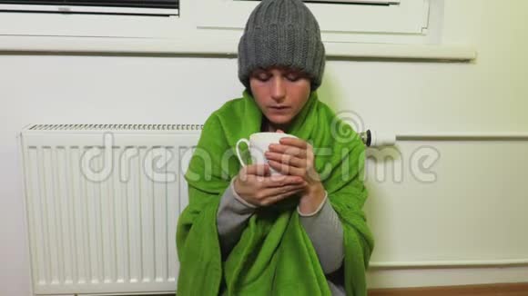 女人在暖气片附近取暖喝茶视频的预览图