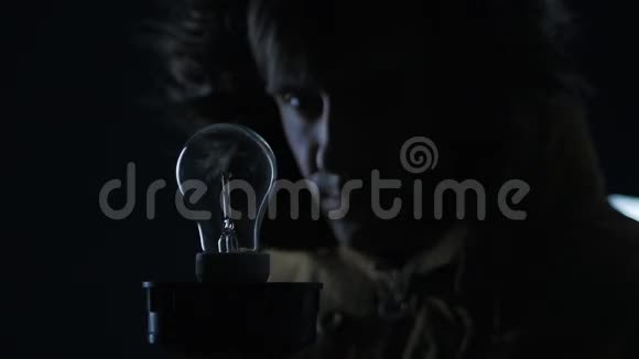 男人在黑暗的房间里点燃一盏灯视频的预览图