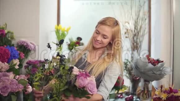 年轻的女性花店布置现代花束年轻英俊的花店工作花束慢动作视频的预览图