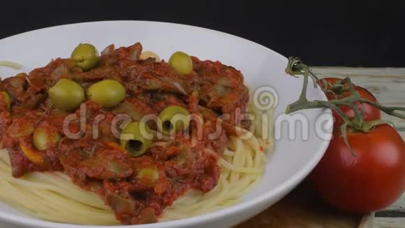 木桌上放有牛肉番茄酱和橄榄的意大利面旋转射击4K决议视频的预览图