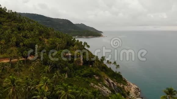 空中无人机俯瞰异国天堂热带海岸悬崖火山石覆盖着绿色丛林视频的预览图