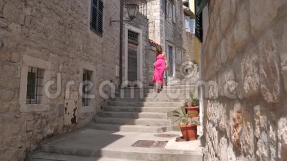 穿着粉色衣服的年轻美女走上古石城的楼梯视频的预览图