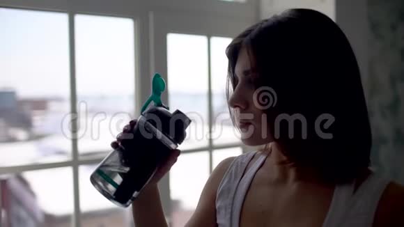 健身妇女从瓶子里喝水肌肉发达的年轻女性在健身房休息锻炼视频的预览图