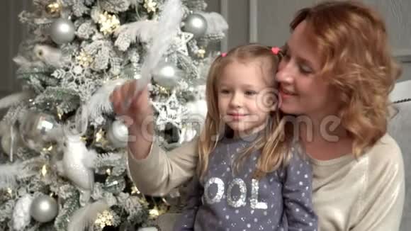 母亲和女儿我认为圣诞球坐在冷杉树的沙发上带着金发的母亲视频的预览图