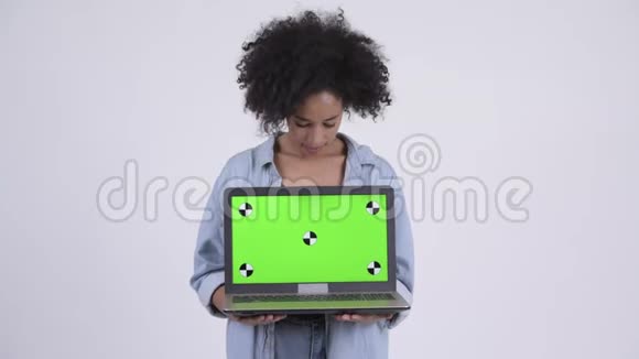 年轻快乐的非洲女人一边思考一边展示笔记本电脑视频的预览图