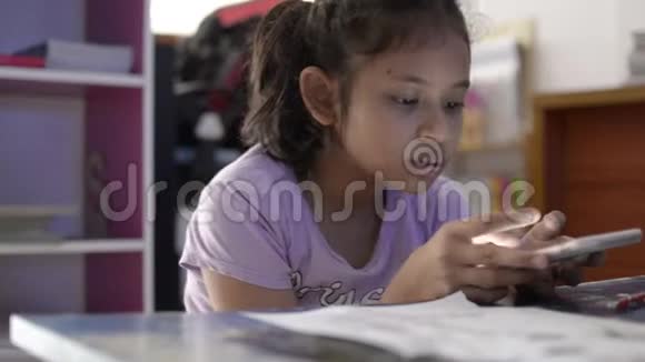 小可爱的亚洲女孩在学习桌上用手机看视频视频的预览图