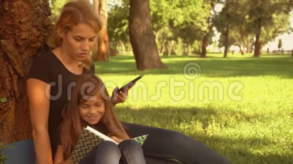 母亲和女儿坐在树旁视频的预览图