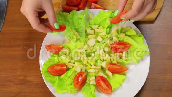 女性手把樱桃番茄片放在一盘沙拉里视频的预览图