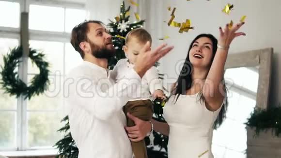 年轻的一家人带着他们可爱的小宝宝兴奋不已到处都是闪闪发光的纸屑在庆祝视频的预览图