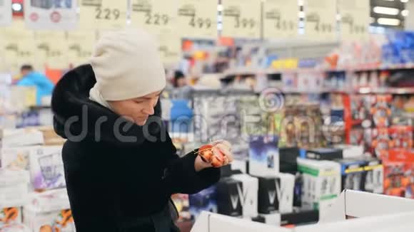 一个穿黑色外套的女人为圣诞树选择圣诞装饰品圣诞节购物视频的预览图