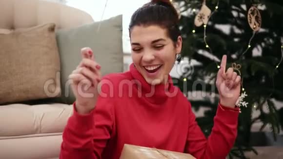 微笑友好迷人的年轻女子坐在圣诞树旁用火花和火花庆祝圣诞节视频的预览图