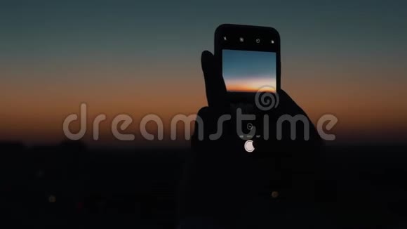 日落时分女孩在智能手机上拍了一张城市视频的预览图