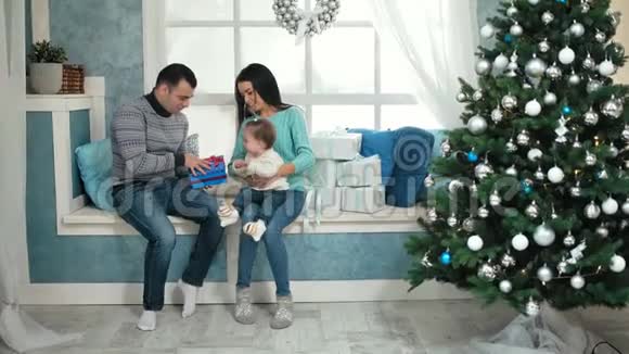 美丽的圣诞幸福家庭小女孩穿着针织毛衣坐在窗台上视频的预览图
