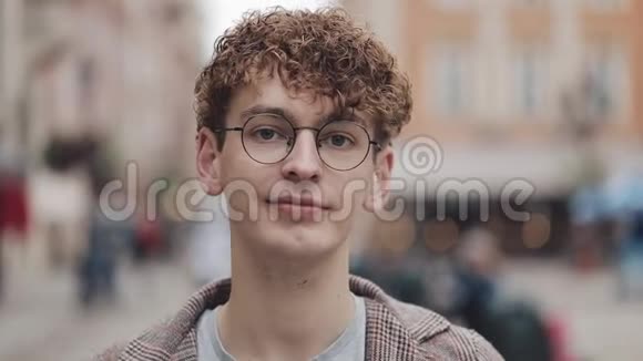 年轻的嬉皮士戴着眼镜站在城市街道上看镜头的肖像旅游旅游视频的预览图