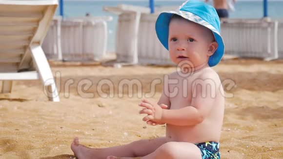 小男孩在海滩上潮湿的沙滩上玩耍他学会爬行波浪拥抱他视频的预览图