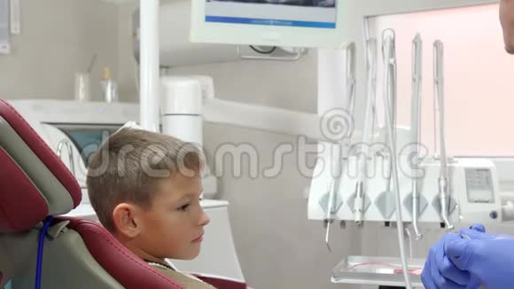 戴橡胶手套的专业牙科医生在设备的背景下将正畸板贴在牙齿上给的牙齿上视频的预览图
