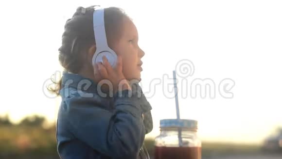 戴耳机的小女孩听音乐喝鸡尾酒果汁冰沙视频的预览图