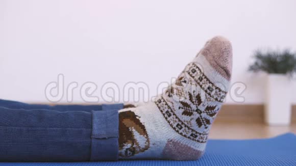 一个穿暖和针织袜子的女人做早操而坐着把手指伸到脚趾上视频的预览图