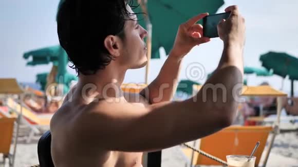 年轻人用手机在海滩拍照视频的预览图