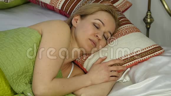 金发女人醒来看着闹钟把它藏在枕头下面慢动作视频的预览图