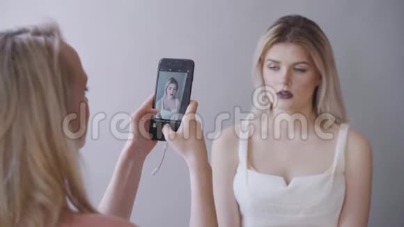 化妆师在电话里给模特拍照深唇灰色背景化妆视频的预览图