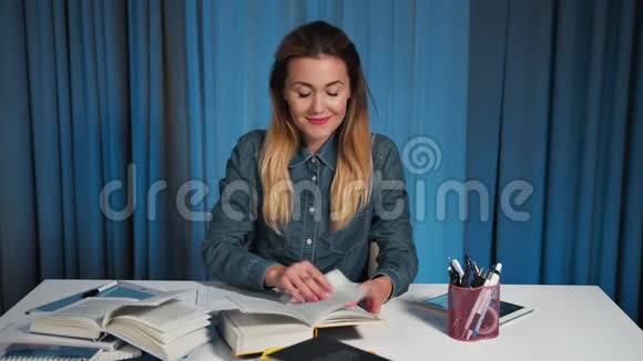 一个穿牛仔衬衫的快乐学生读一本书在工作簿上写作视频的预览图
