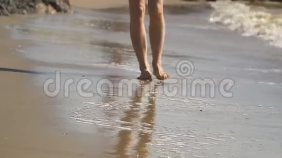 美丽的女人腿沿着沙滩奔跑在水里散步视频的预览图