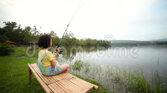 快乐的女孩拉着鱼竿在湖边钓鱼视频的预览图