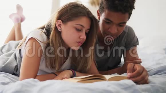 有魅力的非洲男人和他的女朋友一起躺在床上在卧室里大声看书视频的预览图