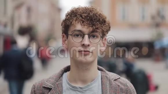 年轻的嬉皮士戴着眼镜站在城市街道上看镜头的肖像旅游旅游视频的预览图