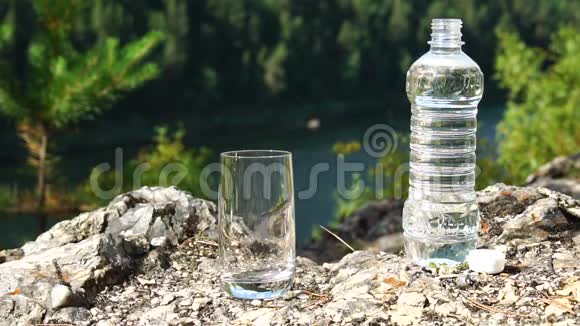 人们把干净的水从瓶子里倒入山区的玻璃里健康生态主题慢动作视频的预览图