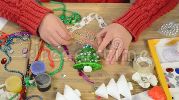 小女孩正在为假期做装饰工艺品及玩具圣诞树等画水彩上景艺术作品视频的预览图