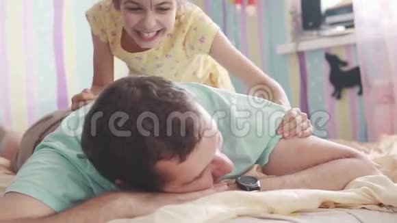 快乐的小女儿爬上父亲的背上吻他小父亲和小女儿一起玩视频的预览图