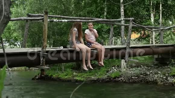 青少年坐在一座山河上一座狭窄的木桥上野营和冒险概念视频的预览图