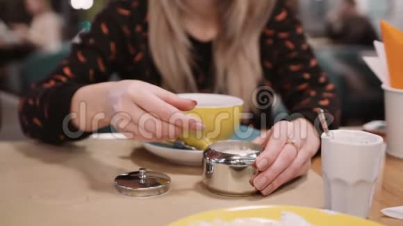 一个身份不明的女人用勺子往餐馆的杯子里倒糖慢动作视频的预览图