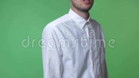 带胡须的年轻人穿着白色衬衫在镜头前边讲边展示带有色度的平板电脑视频的预览图