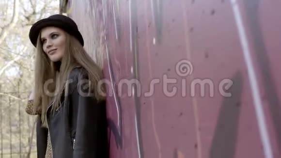 性感模特女人戴着帽子站在墙边摆姿势行动戴着帽子站着的时髦女人视频的预览图