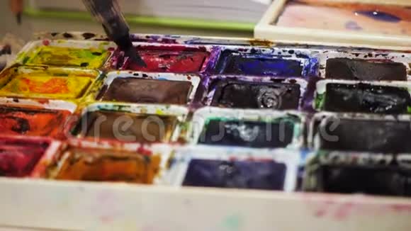 艺术家用画笔在调色板上混合水彩视频的预览图