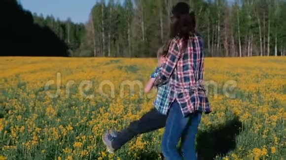 妈妈和儿子正在用黄花牵着手在田野上旋转家人在春天散步视频的预览图