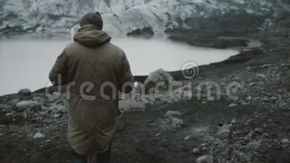 一个人在冰泻湖散步的年轻人的后景在冰岛冰川附近的火山山徒步旅行视频的预览图