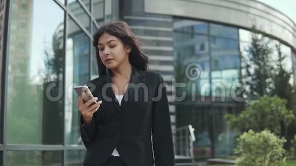 漂亮的商务女性在现代商务中心的背景下使用智能手机视频的预览图