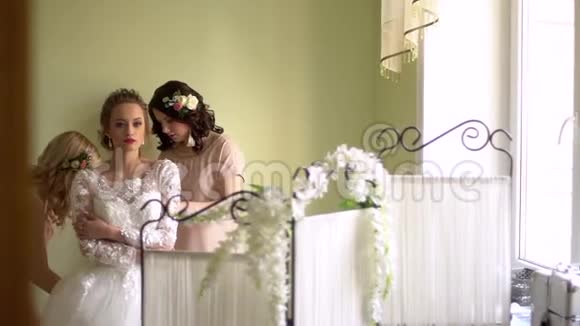 两个女朋友帮新娘穿衣每个人都在微笑女孩们都用花装饰视频的预览图