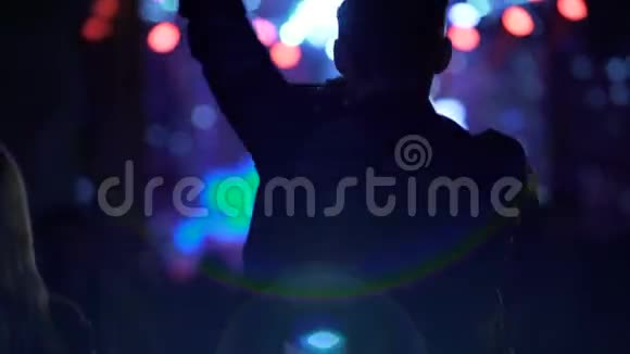 快乐的男性舞蹈挥舞双手在夜总会的智能手机上拍摄音乐会视频的预览图