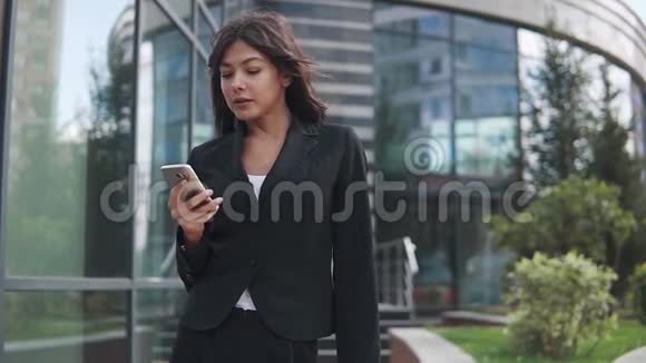 漂亮的商务女性在现代商务中心的背景下使用智能手机视频的预览图