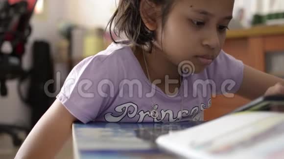 小可爱的亚洲女孩在学习桌上用手机看视频视频的预览图