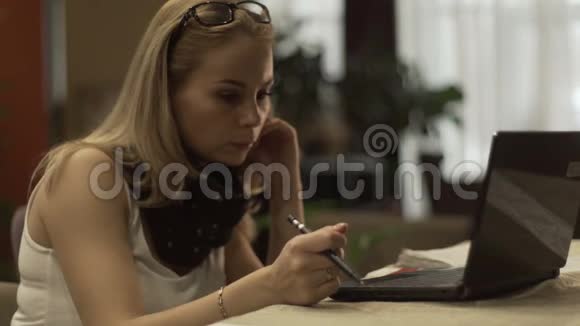 年轻的金发女郎在室内背景的键盘笔记本上打字视频的预览图