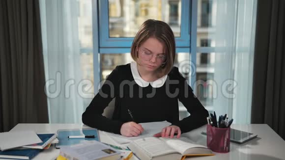 一个沮丧的女学生做作业读一本书然后写在练习本中当它穿过并生气时视频的预览图