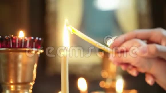 一只雌手牵着一个孩子她的手在教堂里点燃一支蜡烛视频的预览图