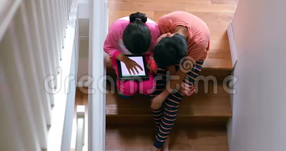 孩子们坐在楼梯4k时使用数字平板电脑视频的预览图